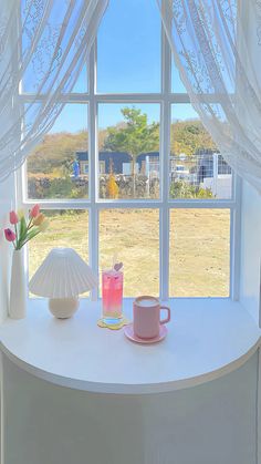 a table with two cups and a vase on it next to a window sill