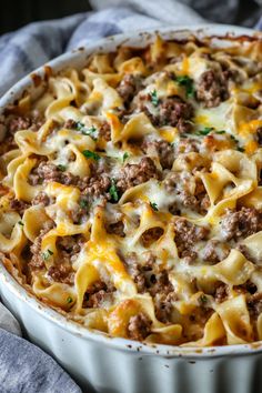 a casserole dish with meat, cheese and sauce in it on a blue towel