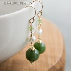 "Here is a simply elegant pair of green nephrite jade ball earrings set with white freshwater pearls and green peridot on 14kt gold fill hooks. The jade balls are about 10mm, the pearl is about 5mm, and the peridot is about 3mm. The earrings hang about 1 1/2\" Jade is the 35th annivesary stone and a good luck healing stone. - Gift packaging included - Ready to ship Please read our shop policies before committing to purchase: http://www.etsy.com/shop/jadepeony/policy If you have any questions, pl Classic Green Pearl Drop Jewelry, Green Round Classic Pearl Earrings, Jade Pearl Drop Earrings As Gift, Classic Green Pearl Earrings As Gift, Green Round Pearl Drop Jewelry, Classic Green Pearl Earrings For Gift, Elegant Green Gemstone Beaded Earrings, Green Pearl Dangle Earrings, Green Dangle Pearl Earrings