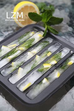 lemon wedges are being served on an ice tray with mint leaves and lime slices