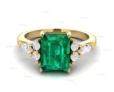 an emerald and diamond ring with three diamonds on the side, set in yellow gold