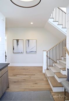 an open floor plan with stairs leading up to the second floor and two paintings on the wall