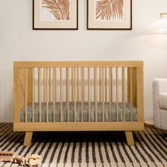 a baby crib in a room with two pictures on the wall