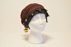 a white mannequin head wearing a green and red knitted hat with bells