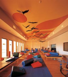 a large room filled with lots of blue and orange mats on top of wooden flooring