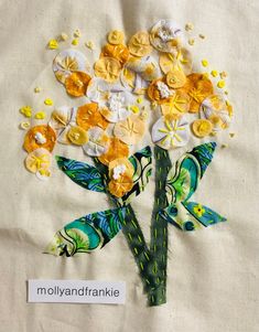 a bouquet of flowers made out of fabric and buttons on a piece of white linen