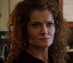 a woman with curly hair looking at the camera