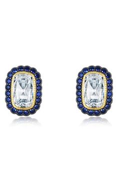 Sparkling stud earrings take inspiration from art deco opulence with a bold simulated diamond hugged by a scalloped halo of created sapphires. 1/4"W x 1/2"L Post back Total stone weight: 6.62ct. Sterling silver/gold plate/black rhodium plate/simulated diamond/lab-created sapphire Imported Fine Jewelry Sapphire Earrings With Halo Design, Sapphire Earrings With Halo Design, Classic Sapphire Diamond Earrings With Halo Design, Luxury Blue Halo Design Earrings, Luxury Sapphire Halo Earrings, L Post, Halo Stud Earrings, Halo Earrings Studs, Halo Earrings