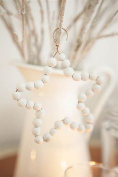 a star ornament hanging from a twig in front of a white vase