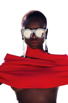 a woman wearing sunglasses and a red dress with polka dots on her face, standing in front of a white background