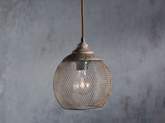 a light that is hanging from a wire on a wall with concrete walls in the background