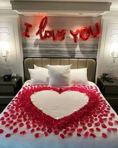 a bed with rose petals on it and the words i love you above it