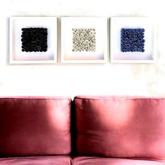 three framed pictures hang on the wall above a red couch