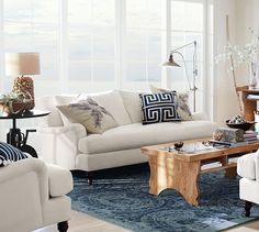 a living room filled with white furniture and lots of window sill space in front of it