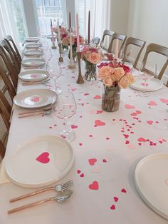 the table is set for valentine's day with pink flowers and hearts on it