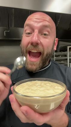 a man holding a bowl of food in front of his face with a spoon sticking out of it