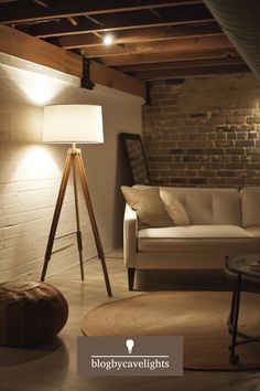 a living room filled with furniture and a lamp next to a white couch in front of a brick wall