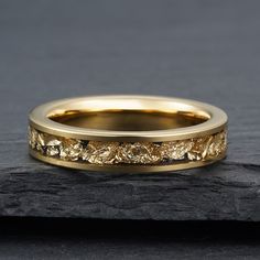 a yellow gold wedding ring on top of a rock