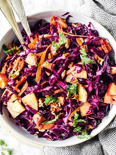 a white bowl filled with red cabbage and apple slices