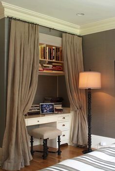 a bedroom with a desk, chair and bookshelf next to a window covered in curtains