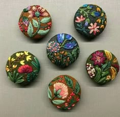 six different colored flowers are shown on the buttons in this set, each with an individual's own design