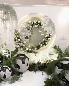 the display is decorated with white flowers and greenery in front of a circular mirror