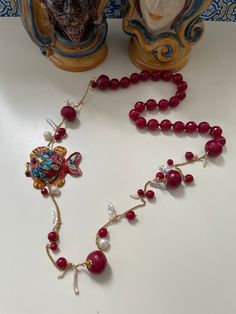 ✔️Sicilian style necklace! Made with string of red Agate faceted pearls, individually knotted, gold plated stainless steel chain, natural freshwater pearls and scaramazza pearls and small smooth red agate pearls. The lively jewel is completed by a hand-painted Caltagirone ceramic fish. Wear beautiful Sicily and always carry it with you with this unique necklace! ✔️DETAILS: 🟩 Materials: Agate Stainless steel Gold River pearls Scary pearls Caltagirone ceramics 🟧🟧Dimensions: Necklace length 85 c Elegant Red Beaded Necklaces With Natural Stones, Elegant Red Beaded Necklace With Natural Stones, Elegant Red Agate Necklace, Luxury Handmade Red Jewelry, Elegant Red Pearl Necklace Gift, Handmade Red Coral Pearl Necklace Gift, Agate Beaded Chain Necklace For Gift, Handmade Elegant Red Coral Pearl Necklace, Red Pearl Chain Necklace As Gift