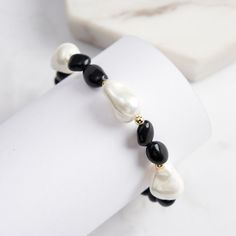 Step into a world of refined elegance with our Baroque Pearl Obsidian Bracelet, a striking piece that effortlessly blends classic sophistication with modern design. This bracelet features lustrous Baroque Shell Pearls, known for their unique, organic shapes that radiate an exquisite, natural beauty. The deep, glossy Obsidian stones provide a dramatic contrast, exuding an air of mystery and protection, while golden accents add a touch of warmth and luxury.   Whether paired with a sleek evening go Elegant Black Beaded Bracelets, Adjustable Black Pearl Beaded Bracelets, Black Pearl Bracelets With Round Beads, Black Beaded Pearl Bracelets, Elegant Beaded Pearl Stretch Bracelet, Elegant Pearl Beaded Stretch Bracelet, Elegant Black Beaded Bracelets Gift, Elegant Black Beads Bracelet For Formal Occasions, Elegant Black Beaded Bracelets For Formal Occasions