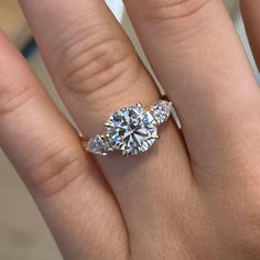 a woman's hand with a three stone ring on top of her wedding band