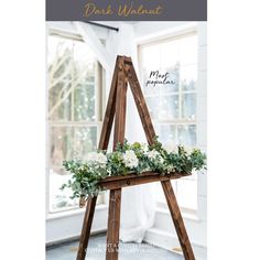 a wooden easel with white flowers and greenery