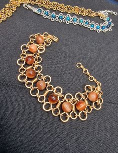 a close up of a necklace on a black surface with gold chains and beads around it