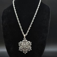 This vintage Trifari necklace features a 2'D silver tone filigree flower pendant on a 22" L silver tone chain. It is signed with the older crown Trifari mark on the bail Silver Flower Pendant Costume Jewelry, Silver Metal Necklace In Flower Shape, Vintage Silver Flower-shaped Necklace, Vintage Silver Flower Shaped Necklace, Silver Metal Pendant Flower Necklace, Silver Metal Flower Pendant Necklace, Silver Medallion Necklace Costume Jewelry, Silver Medallion Costume Jewelry Necklace, Silver Filigree Medallion Necklace