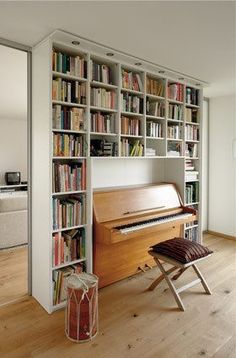 a living room filled with lots of furniture and bookshelves next to a piano