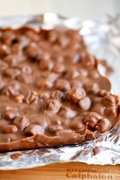 a piece of chocolate cake sitting on top of aluminum foil covered in melted chocolate chips