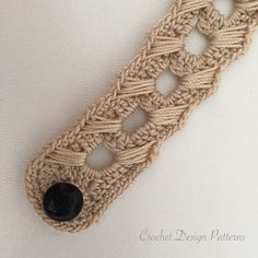 a piece of crocheted fabric with buttons attached to the end and two holes in the middle