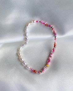 a white bracelet with pink and yellow beads