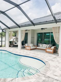 an outdoor pool with lounge chairs next to it and a covered patio area in the background