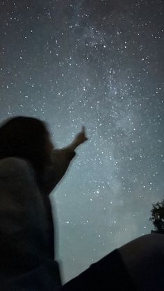 a person looking up at the stars in the night sky with their arms outstretched to the side