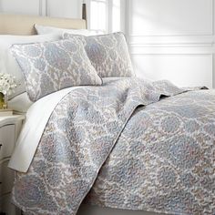 a bed with white and blue comforters in a bedroom