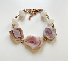 Welcome to our enchanting collection of handcrafted gemstone bracelets, where elegance meets the healing power of nature's most precious gems. Our Pink Quartz and Agate beaded bracelet is a stunning embodiment of beauty and positive energy. Indulge yourself or surprise a loved one with this exquisite pink quartz bracelet, a symbol of love, compassion, and emotional healing. Crafted with delicate precision, each pink quartz crystal bead radiates soft, soothing energies, offering comfort and tranquility to your everyday life. The gentle, blushing hues of Pink Agate in this bracelet add a touch of sophistication and a dash of serenity. Known for its stabilizing properties, pink agate enhances inner strength, balancing the mind, body, and spirit. It's a stone that promotes harmony and a sense Pink Healing Bracelets With Natural Stones, Pink Spiritual Crystal Bracelet With Natural Stones, Healing Pink Bracelets With Natural Stones, Spiritual Pink Crystal Bracelet With Natural Stones, Adjustable Pink Agate Bracelet, Adjustable Pink Agate Bracelets, Pink Agate Crystal Bracelet As A Gift, Bohemian Rose Quartz Crystal Bracelet With Natural Stones, Bohemian Pink Agate Bracelets