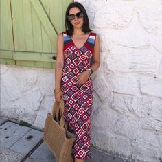 a woman standing next to a white wall holding a brown bag