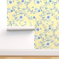 an empty room with yellow wallpaper and blue flowers on the wall, next to a white door