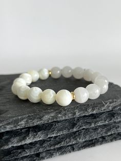 💎 MATERIAL DETAILS ○ 10mm Mother of Pearl Shell → soothing, stimulates adaptability, intuition, and imagination  ○ 10mm White Jade → abundance, prosperity, detox, calmness, and love ○ 6mm 18k gold plated spacers ○ High quality, resistant, and flexible elastic cord (double-corded) 💯 QUALITY & CRAFTSMANSHIP ○ Materials are handpicked, inspected, and handled with the utmost quality and care ○ Double-corded with high quality elastic cord - this means our bracelets have 2x the durability of other s Elegant 8mm Beads Bracelet For Meditation, Elegant 8mm Beads Stretch Bracelet For Meditation, Elegant Stretch Bracelet With 8mm Beads For Meditation, Elegant Agate Stretch Bracelet Gift, White Minimalist Crystal Bracelet For Everyday, Minimalist White Crystal Bracelet For Everyday, Elegant Beaded Bracelets For Meditation, Elegant White Moonstone Beaded Bracelets, White Natural Stone Round Bracelets