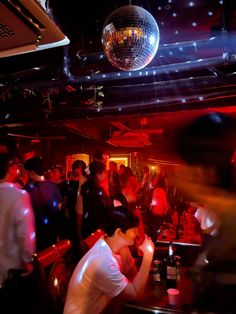 people are dancing in a club with disco balls