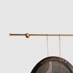 a clock hanging from a metal bar on a white wall with a gold chain attached to it