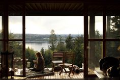 a woman sitting on top of a wooden floor next to a window filled with lots of windows