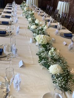 a long table with white flowers and place settings