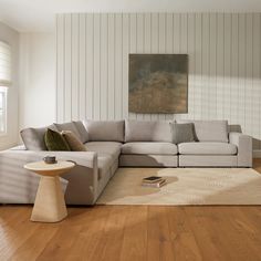 a living room with white walls and wood flooring on the wooden floor, along with a large sectional couch