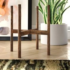 a wooden chair sitting next to a potted plant on top of a hard wood floor