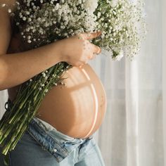 a pregnant woman holding flowers in her belly